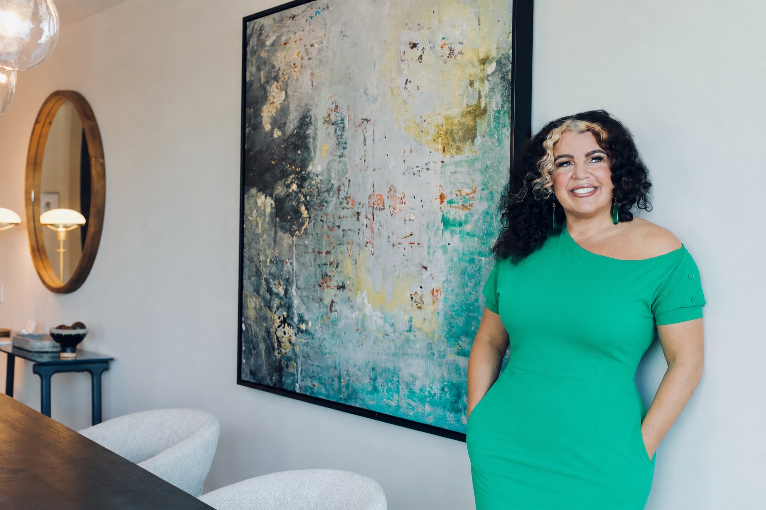 Katina Benenate in a green dress beside abstract artwork in an elegant interior
