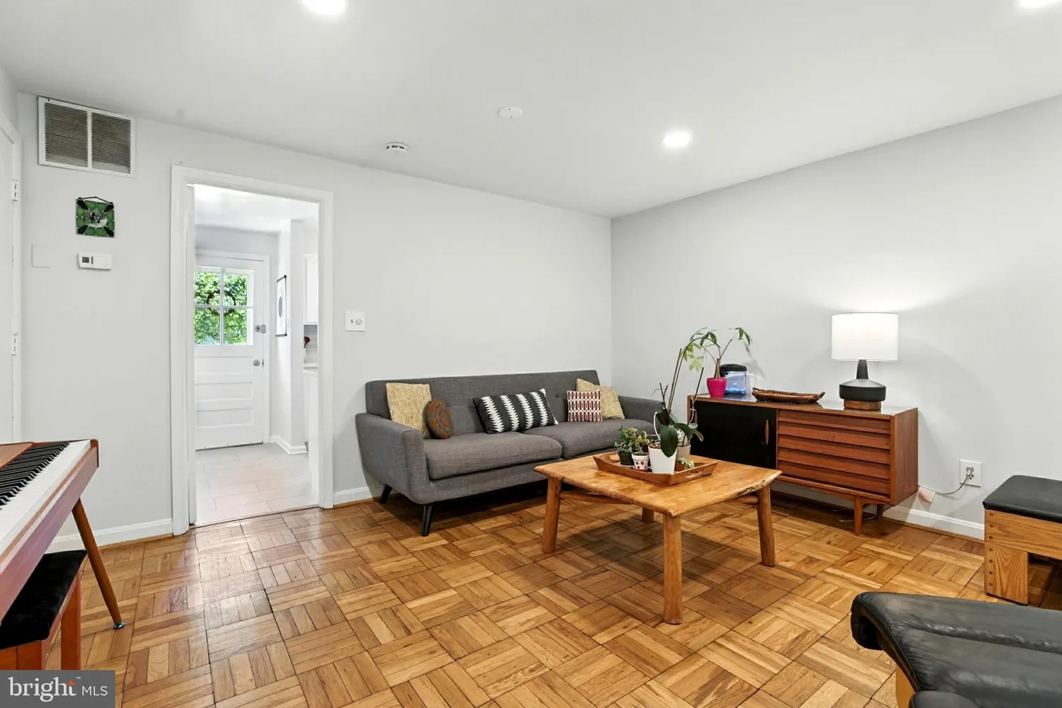 Living room with parquet hardwood floors, gray sofa, and wood coffee table
